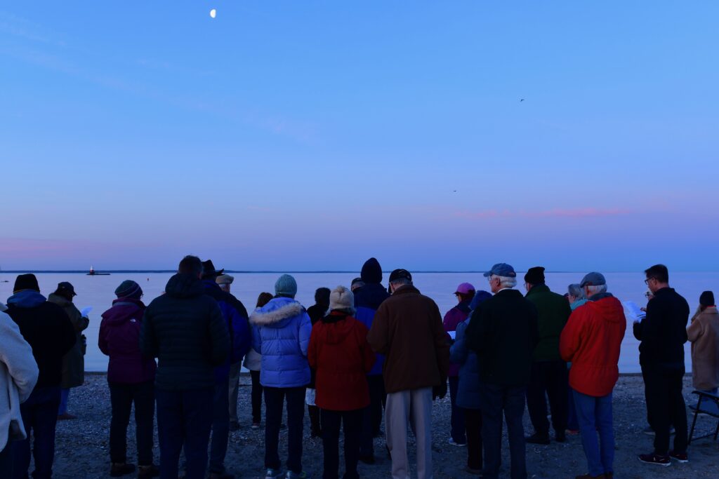 People standing on a beach with Moon overhead during the Sunrise service